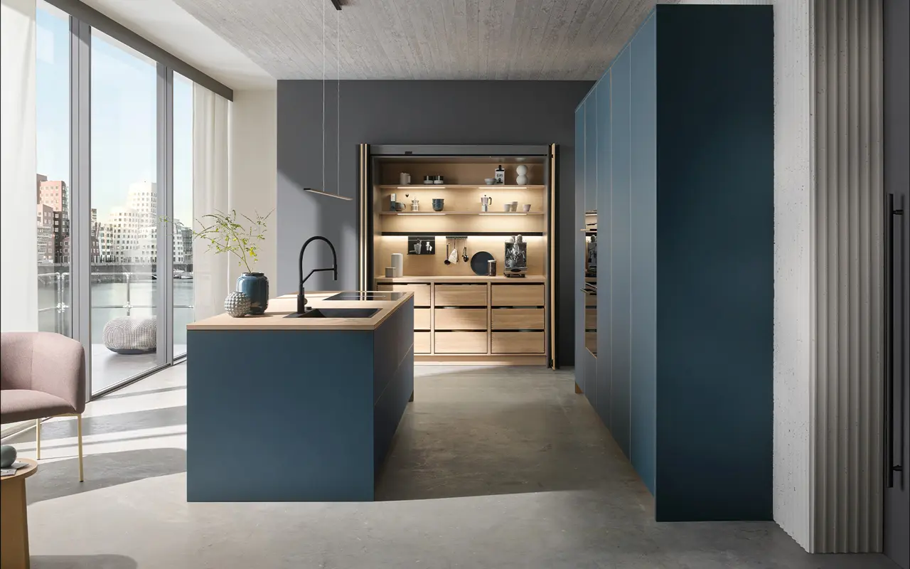 Designküche in Dunkelblau mit heller Holzarbeitsplatte und integrierter Nischenbeleuchtung. Große Fensterfront mit Stadtblick und stilvolle Kombination aus modernen und natürlichen Elementen.